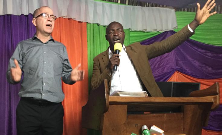 Craig Bailey (left) participates in worship with Ugandan church leaders.